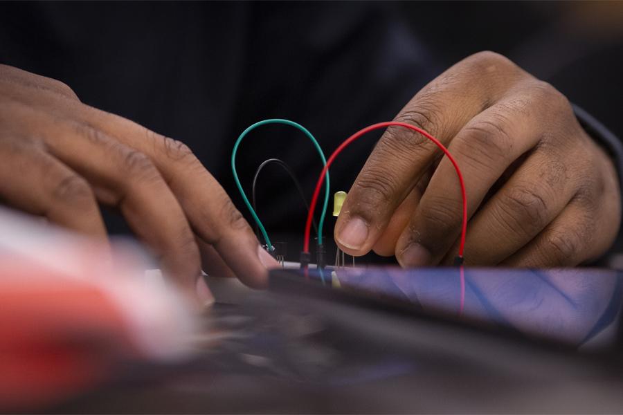 A pair of hands works with a red and green wire.